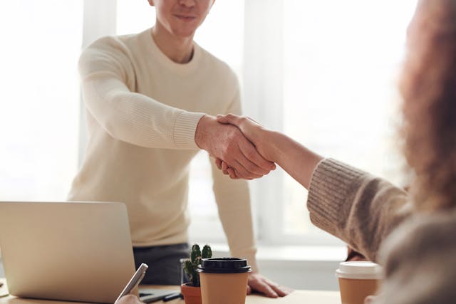 Two people shaking hands over coffee